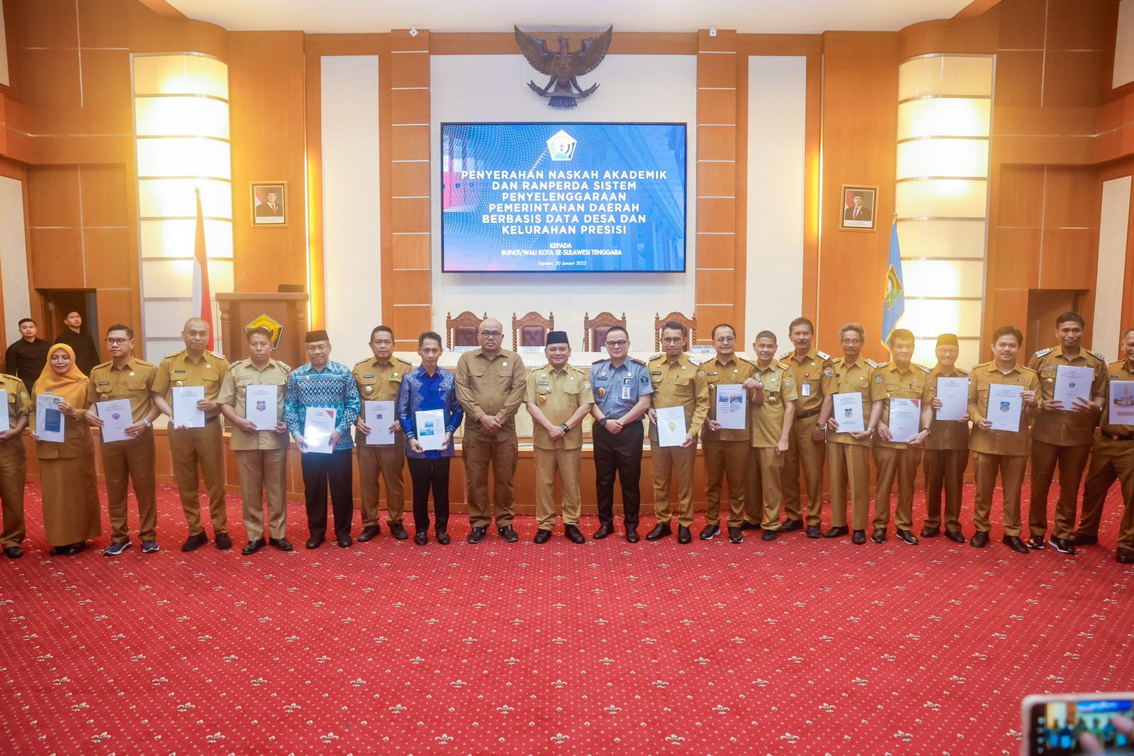 Pj Gubernur Sultra, Andap Budhi Revianto saat menyerahkan Naskah Akademik dan Draf Ranperda mengenai Sistem Penyelenggaraan Pemda Berbasis Data Desa/Kelurahan Presisi (DDP) kepada seluruh Bupati dan Walikota se-Sultra, bertempat di Ruang Pola Kantor Gubernur Sultra.