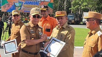 Gubernur Sultra, Andi Sumangerukka saat menyerahkan penghargaan desa tangguh bencana kepada Bupati Buton Utara, Afirudin Mathara. (FOTO: FAYSAL/MS)