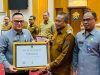 Kepala Kanwil Hukum Sultra, Topan Sopuan, saat menyerahkan penghargaan atas capaian 100 persen pembentukan Pos Bantuan Hukum yang diterima oleh Asisten I Bidang Administrasi Pemerintahan dan Kesra Setda Sultra, Pahri Yamsul, mewakili Gubernur Sultra pada acara pembukaan pelatihan paralegal se-Sultra berlangsung di Aula Pola Kantor Gubernur Sultra. (FOTO: FAYSAL/MS)
