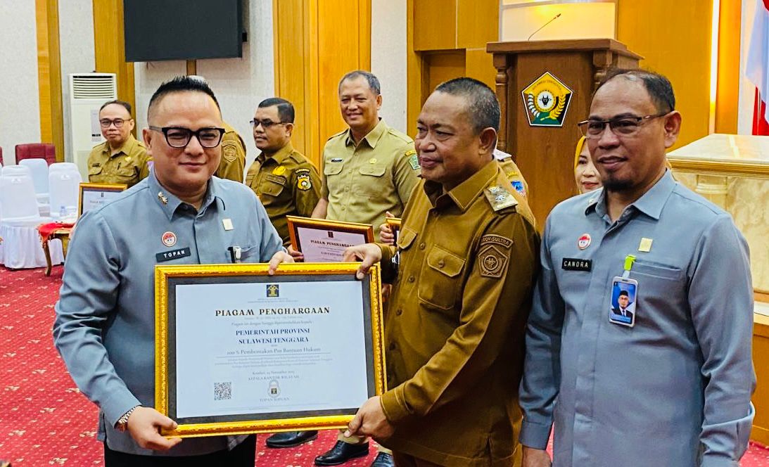 Kepala Kanwil Hukum Sultra, Topan Sopuan, saat menyerahkan penghargaan atas capaian 100 persen pembentukan Pos Bantuan Hukum yang diterima oleh Asisten I Bidang Administrasi Pemerintahan dan Kesra Setda Sultra, Pahri Yamsul, mewakili Gubernur Sultra pada acara pembukaan pelatihan paralegal se-Sultra berlangsung di Aula Pola Kantor Gubernur Sultra. (FOTO: FAYSAL/MS)